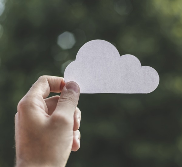 Hand houdt een wolkje van wit papier omhoog als symbool voor de cloud