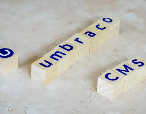 Houten blokjes op een marmeren ondergrond vormen de woorden Umbraco CMS, met een los blokje met het Umbraco-logo