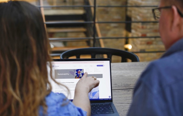 Vrouw wijst een collega op een webpagina met de kop Sustainability op een laptop